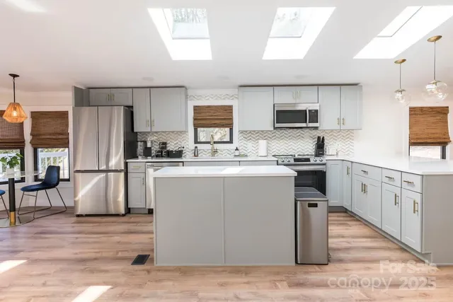 a kitchen with kitchen island granite countertop a sink a stove top oven a refrigerator cabinets and a dining table