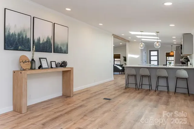 a view of a room with kitchen island stainless steel appliances wooden floor and furniture