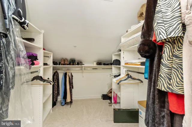 a view of walk in closet with clothes and shoes