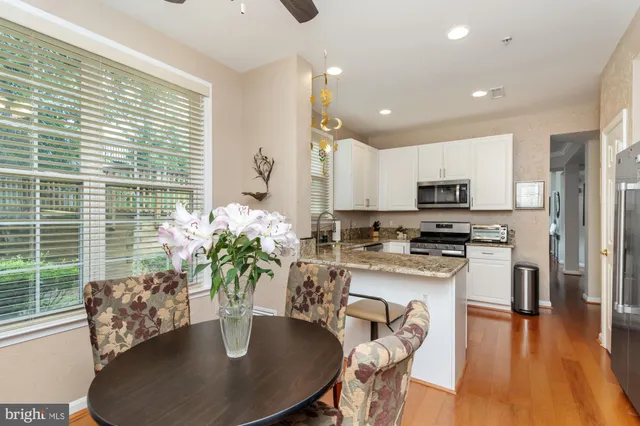 a kitchen with stainless steel appliances granite countertop a dining table chairs and a potted plant