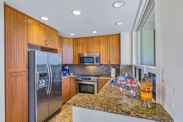 a kitchen with stainless steel appliances granite countertop sink stove refrigerator and cabinets