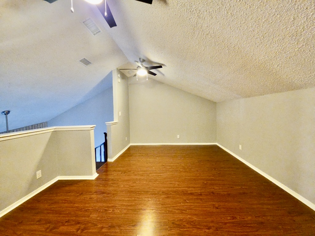 2500 Burleson Road, Unit 521 Austin, TX 78741 - Photo 10 of 20 Spacious upper-level room featuring wood-finish flooring, vaulted ceilings, and a ceiling fan