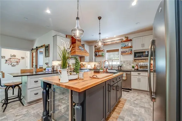 a kitchen with stainless steel appliances granite countertop a refrigerator a sink dishwasher a stove and a dining table with wooden floor