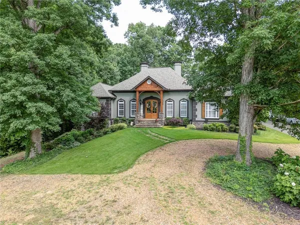 a front view of a house with a yard and large trees