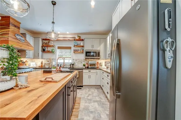 a kitchen with stainless steel appliances granite countertop a refrigerator a stove a sink dishwasher and white cabinets with wooden floor