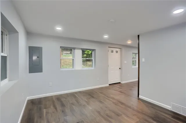 an empty room with wooden floor and windows