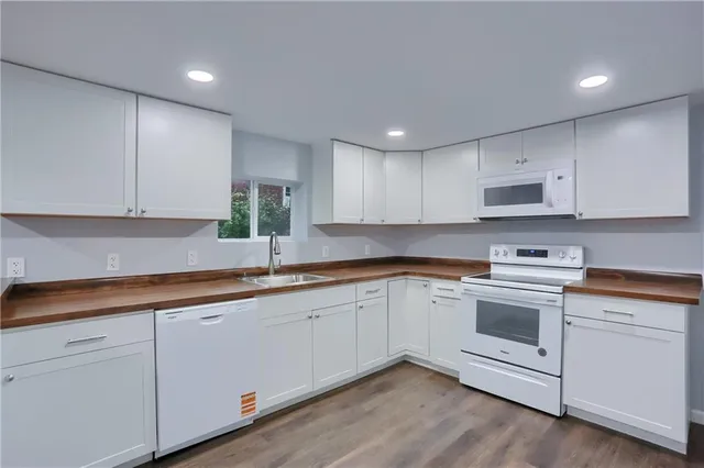 a kitchen with stainless steel appliances granite countertop a stove a sink and white cabinets