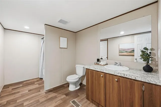 a bathroom with a granite countertop sink toilet and mirror