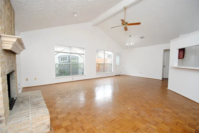 a view of an empty room with a window and kitchen view