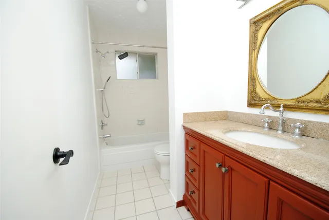 a bathroom with a granite countertop sink mirror and a bathtub