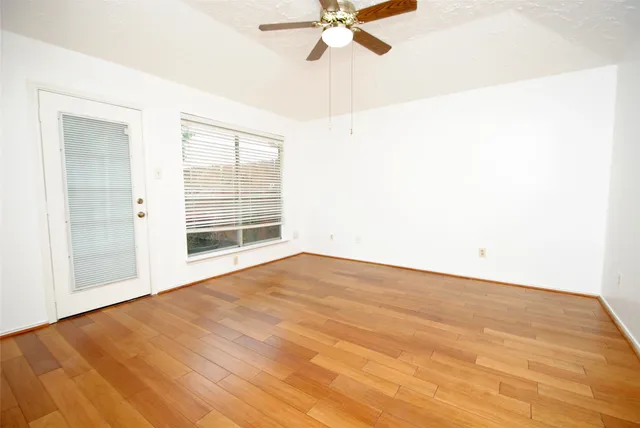 a view of an empty room with wooden floor and a window