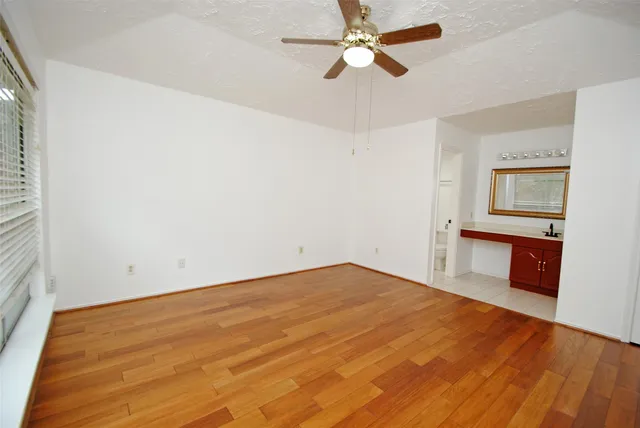 a view of a room with wooden floor and a ceiling fan