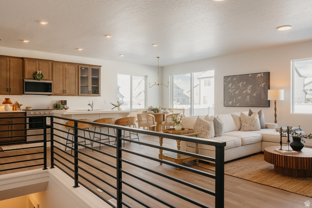 4595 North Fallow Way, Unit 511 Eagle Mountain, UT 84005 - Photo 22 of 32 Kitchen featuring glass insert cabinets, a textured ceiling, stainless steel appliances, wood finish cabinets, and light wood-style floors