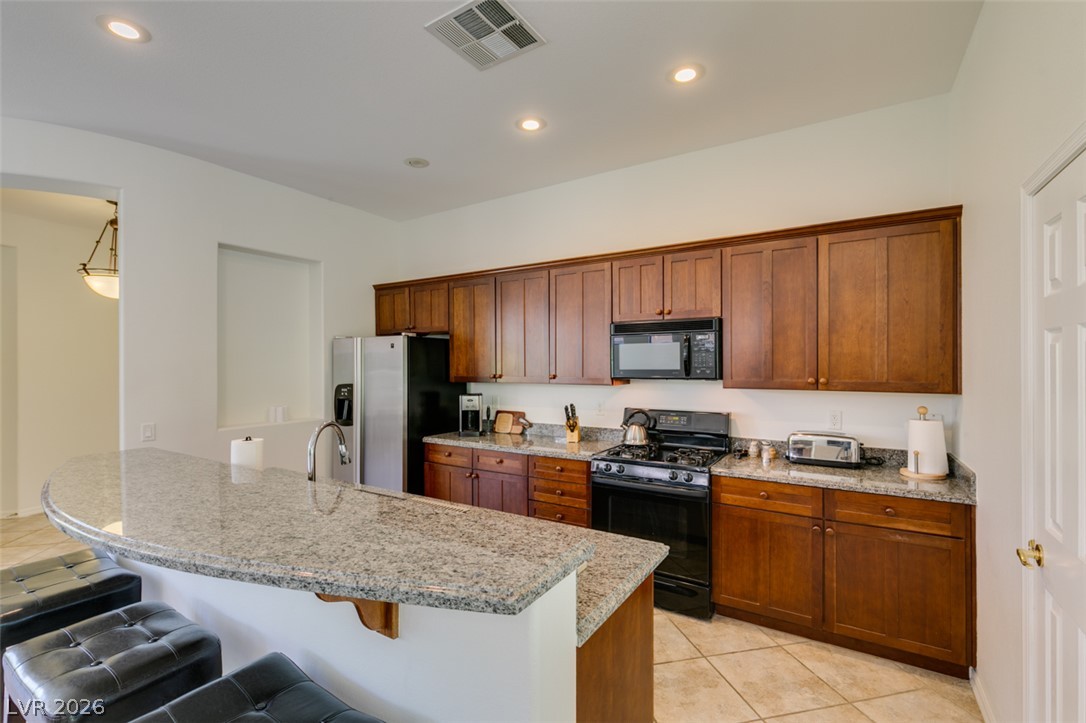8 Kennesaw Road Henderson, NV 89052 - Photo 23 of 44 A well-appointed kitchen features rich wood cabinetry, granite countertops, and modern appliances, perfect for everyday living.