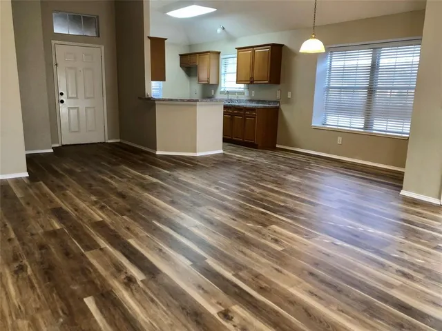 a view of an empty room with a kitchen and wooden floor