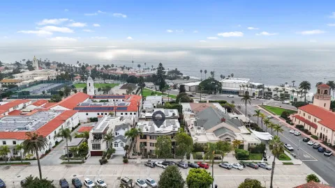 an aerial view of a multi story parking building with yard and mountain view in back