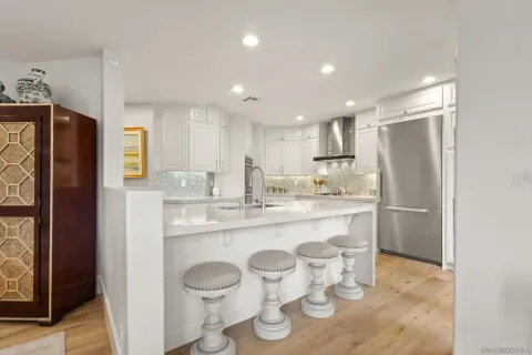 a large white kitchen with kitchen island a sink stainless steel appliances and cabinets