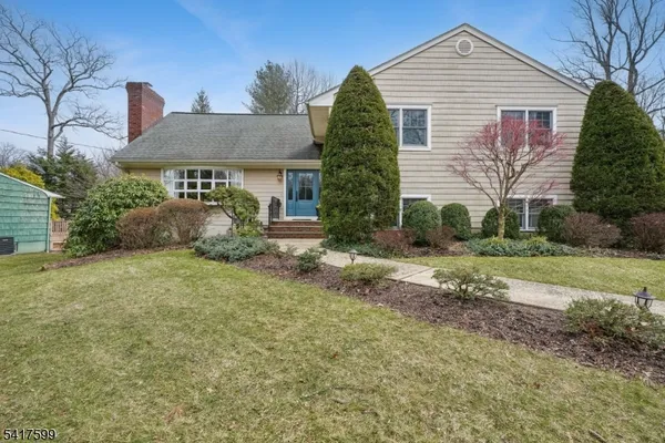 a view of a house with plants and large tree