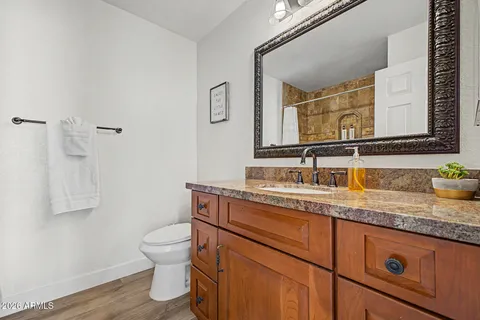 a bathroom with a granite countertop toilet sink and mirror