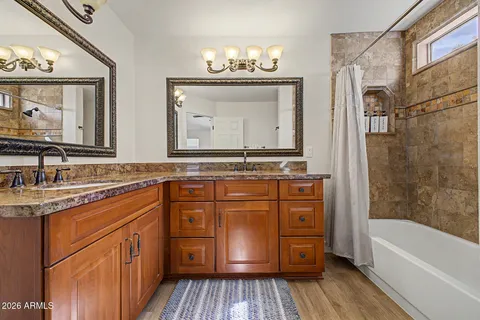 a bathroom with a granite countertop sink a mirror a bathtub and shower