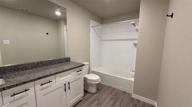 a bathroom with a granite countertop sink a toilet and shower