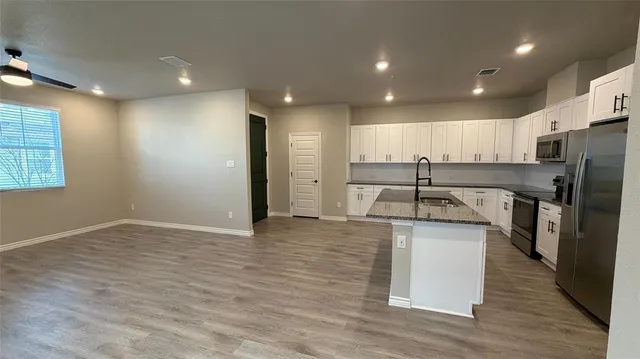 a kitchen with stainless steel appliances granite countertop a stove a sink a refrigerator and a microwave