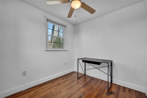 a view of empty room with wooden floor and fan