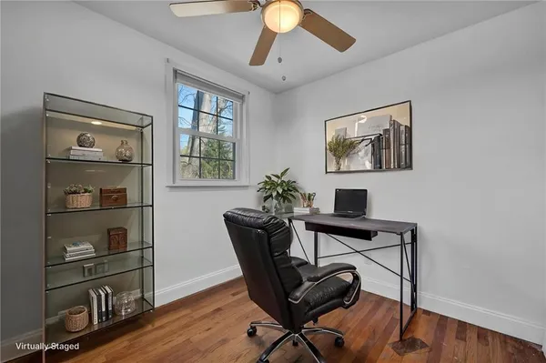 a view of empty room with wooden floor and fan