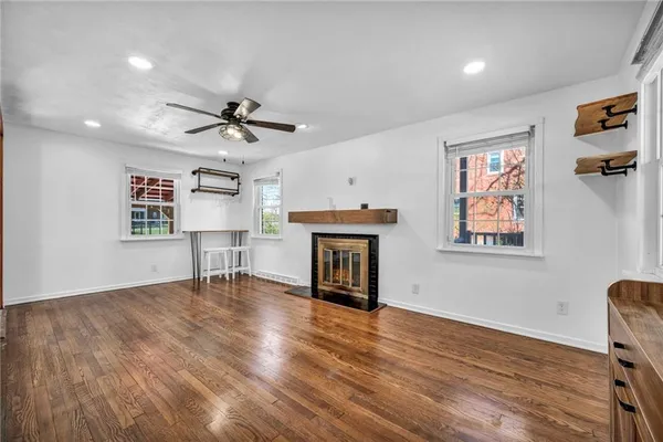 a view of an empty room with a fireplace and wooden floor