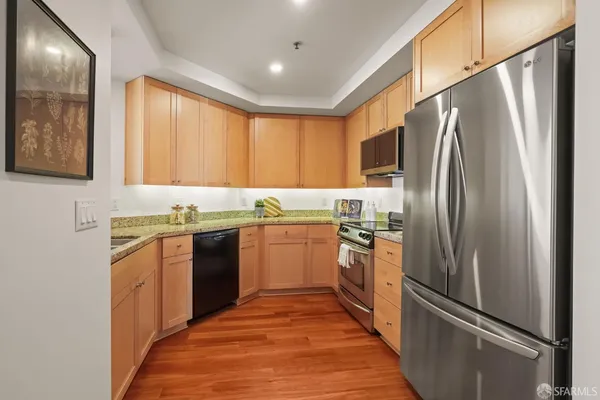 a kitchen with granite countertop stainless steel appliances a refrigerator stove top oven and sink