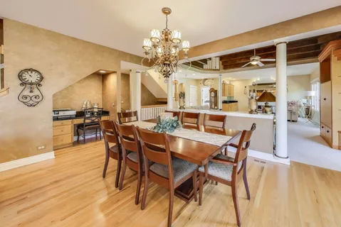 a dining room with wooden floor a chandelier a wooden table and chairs