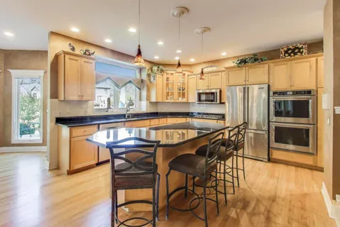 a kitchen with stainless steel appliances granite countertop a table chairs stove and refrigerator