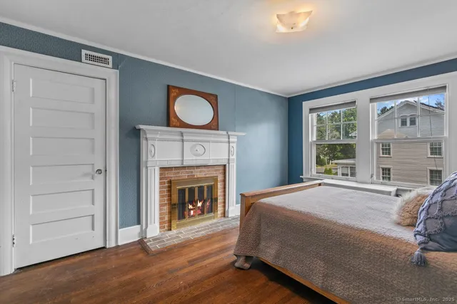 a bed sitting in a bedroom next to a window with a fireplace
