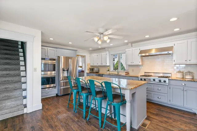 a kitchen with stainless steel appliances granite countertop a table chairs sink refrigerator and cabinets