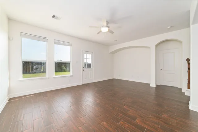 an empty room with wooden floor and windows