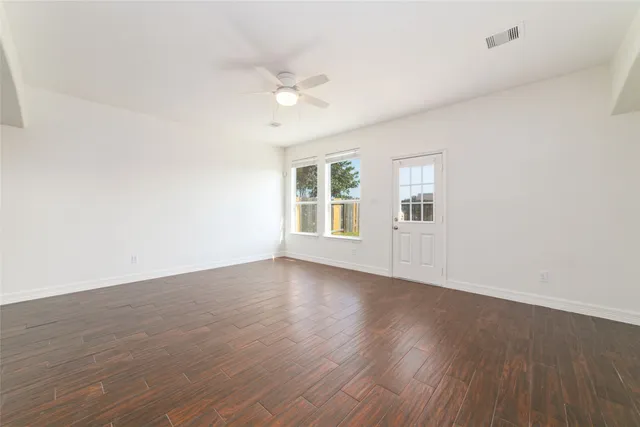 an empty room with wooden floor and windows