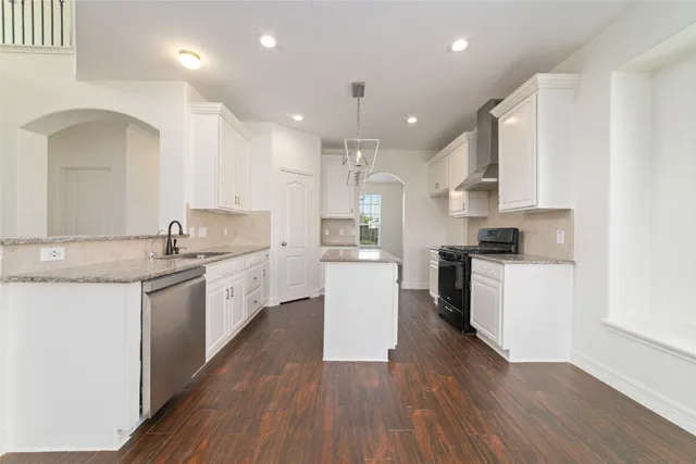 a kitchen with a sink wooden floor stainless steel appliances and cabinets