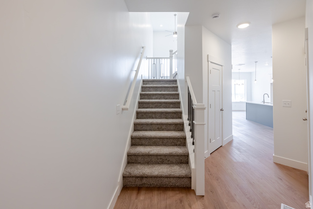 5228 South Acacia Drive, Unit 808 Mapleton, UT 84664 - Photo 14 of 22 Carpeted staircase with white newel posts and black metal balusters, complemented by wood-finish flooring