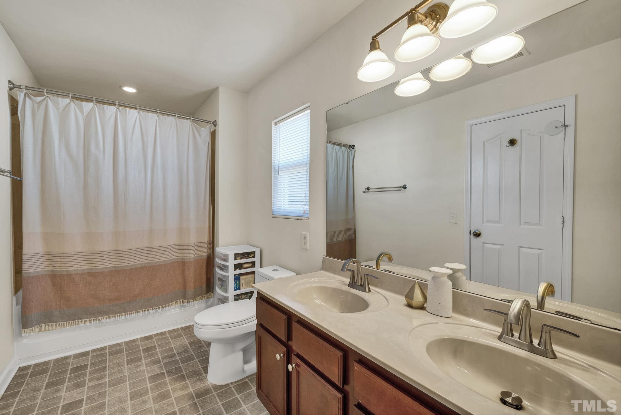 209 Lodestone Drive Durham, NC 27703 - Photo 19 of 30 a bathroom with double vanity sink a toilet a mirror and shower
