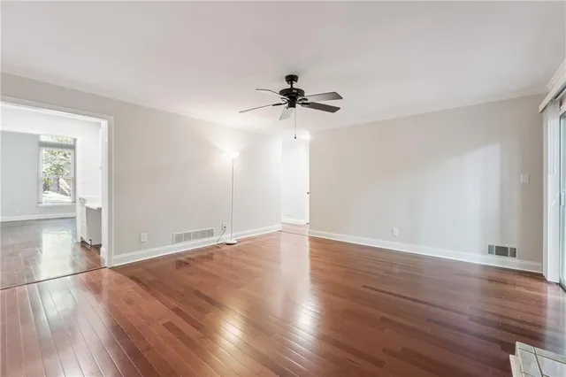 an empty room with wooden floor and chandelier fan