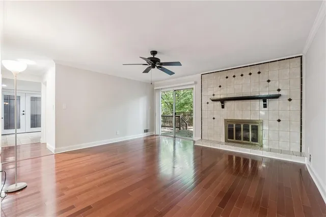 a view of an empty room with wooden floor fireplace and a window