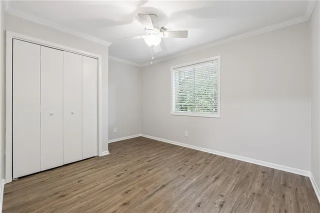 an empty room with wooden floor chandelier fan and windows