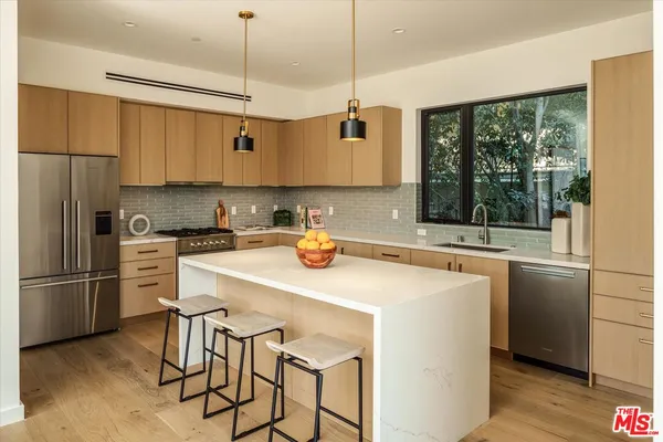 a kitchen with stainless steel appliances granite countertop a refrigerator a sink a stove and white cabinets