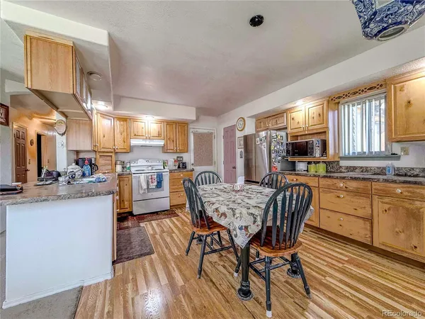 a kitchen with granite countertop a refrigerator a sink dishwasher a dining table and chairs with wooden floor
