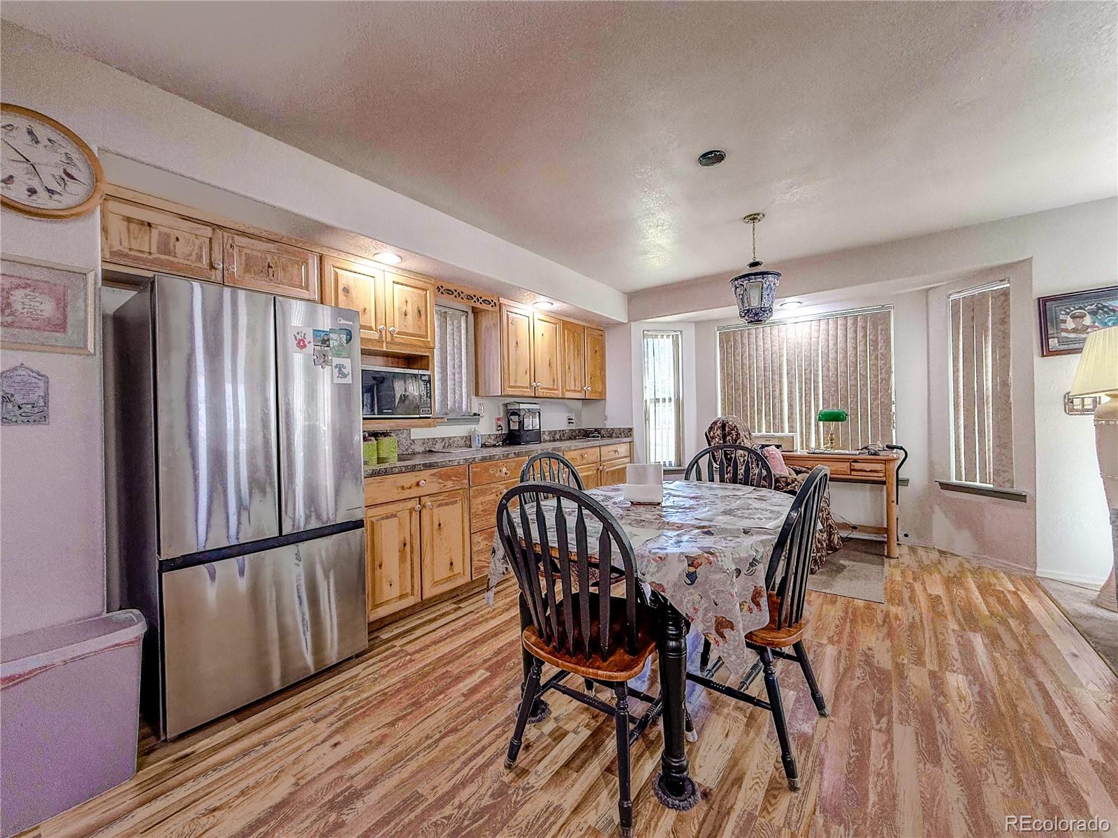 20899 County Rd L.7 San Luis, CO 81152 - Photo 8 of 36 a kitchen with granite countertop a refrigerator a sink dishwasher a dining table and chairs with wooden floor