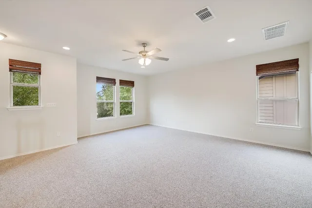 an empty room with windows and ceiling fan