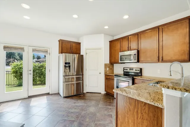 a kitchen with stainless steel appliances granite countertop a refrigerator a stove top oven a sink and dishwasher