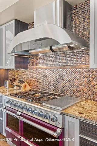 a large kitchen with granite countertop a stove a sink dishwasher and a black countertop with white cabinets