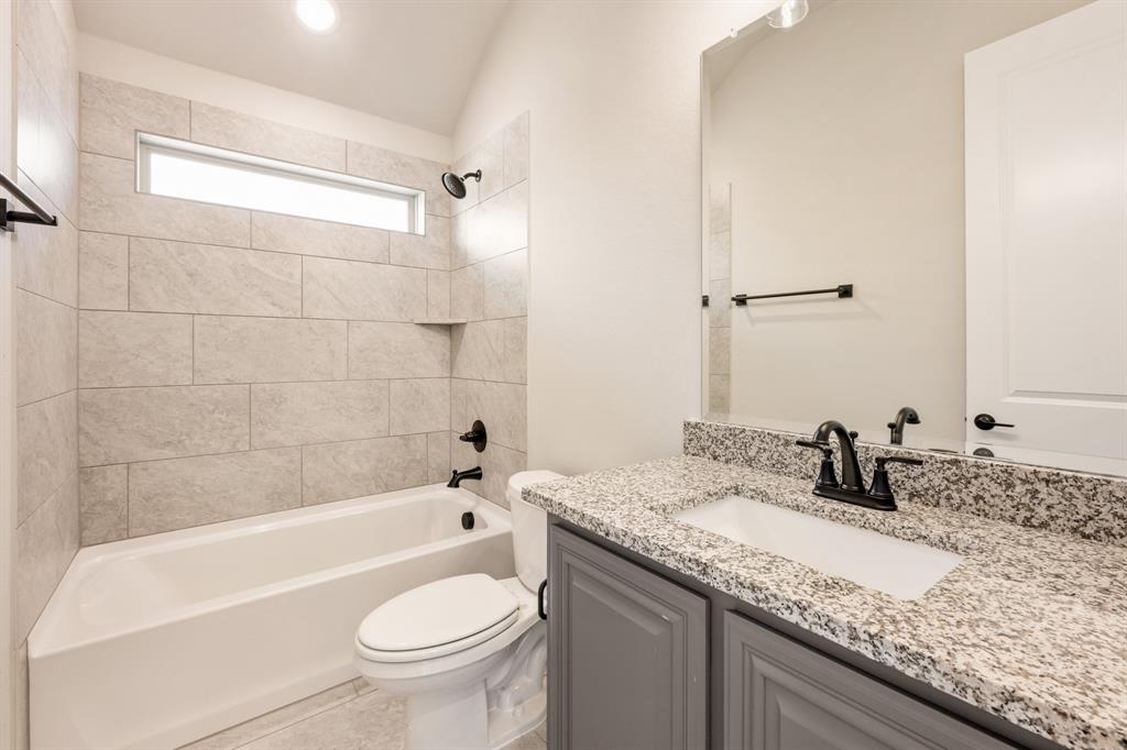 14426 McClint Street Pilot Point, TX 76258 - Photo 27 of 34 a bathroom with a granite countertop sink a toilet a mirror and bathtub