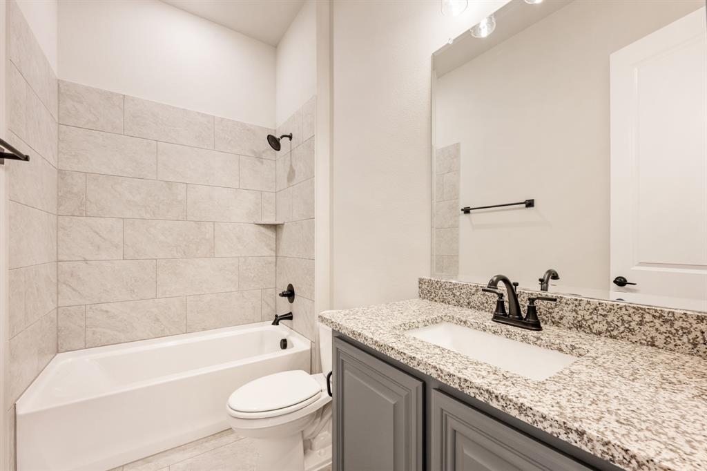 14426 McClint Street Pilot Point, TX 76258 - Photo 29 of 34 a bathroom with a granite countertop sink a toilet and bathtub